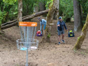 David Boyajian, right, of Portland, throws a disc toward a basket at the Hockinson Meadows Community Park disc golf course. The course is the first 18-holer in Clark County.