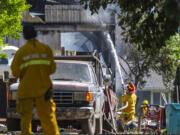 A Vancouver firefighter sprays the outside of a burned building Monday, June 5, 2023, on Northeast 68th Avenue in Vancouver. .