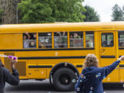 Students wave goodbye to faculty and staff as their bus drives away Tuesday following the last day of school at Eleanor Roosevelt Elementary School.