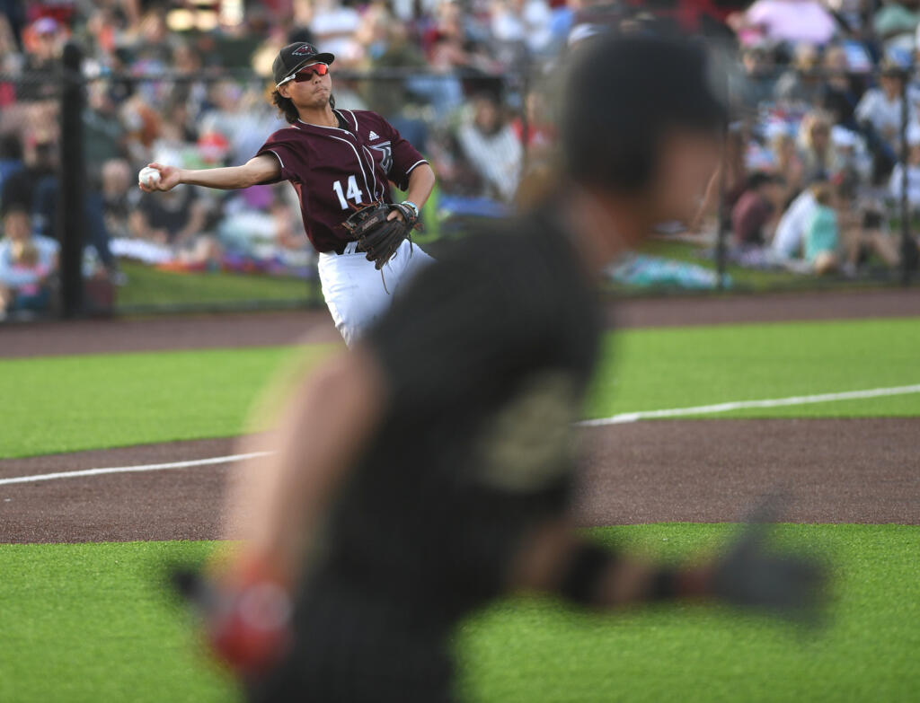 Raptors third baseman Jake Tsukada, left, tosses a ground ball to first base Tuesday, June 27, 2023, during the Raptors’ game against Bend at the Ridgefield Outdoor Recreation Complex.