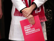 Dr. Erin Berry, Washington State Medical Director for Planned Parenthood of the Great Northwest and the Hawaiian Islands, holds a folder as she listens at a news conference announcing a lawsuit challenging the Trump administration's Title X "gag rule" in Seattle in 2019.