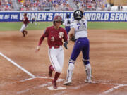 Florida State's Devyn Flaherty (9) scores next to Washington catcher Sydney Stewart during the second inning of an NCAA softball Women's College World Series game Saturday, June 3, 2023, in Oklahoma City.