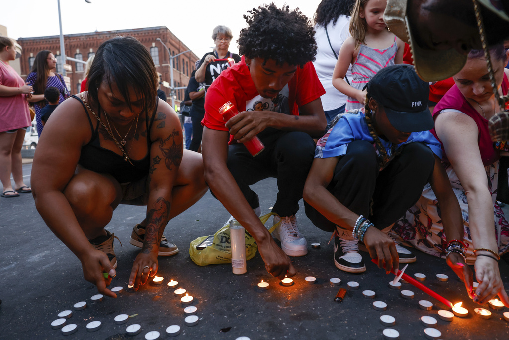 Branden Colvin Jr., center, lights candles for his father, Branden Colvin Sr., with Devina Henderson, left, and Malia Rush, right, during a candlelight vigil for Colvin, Ryan Hitchcock and Daniel Prien, at the site of a building collapse, Sunday, June 4, 2023, in Davenport, Iowa. The three men had been missing since the partial collapse of the apartment building on May 28. Colvin has since been confirmed to have died in the collapse.