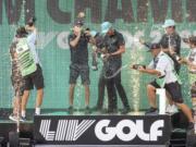 Team champions David Puig, Sebastián Muñoz, Mito Pereira, Captain Joaquín Niemann of Torque GC and their caddies celebrate on stage with the team trophy during LIV Golf DC at the Trump National Golf Club in Washington Sunday, May 28, 2023, in Sterling, Virginia. The most disruptive year in golf ended Tuesday, June 6, 2023, when the PGA Tour and European tour agreed to a merger with Saudi Arabia's golf interests, creating a commercial operation designed to unify professional golf around the world.