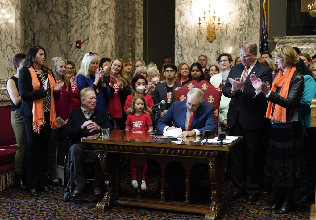 FILE - Washington Gov. Jay Inslee signs House Bill 1240, which prohibits the manufacture, importation, distribution and sale of semi-automatic assault-style weapons in the state, April 25, 2023, at the state Capitol in Olympia, Wash. A U.S. judge on Tuesday, June 6, rejected a request to block a new Washington state law banning the sale of certain semi-automatic rifles, one of three measures recently signed by Inslee in an effort to reduce gun violence.