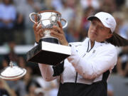 The lid flies off the trophy as Poland's Iga Swiatek celebrates winning the women's final match of the French Open tennis tournament against Karolina Muchova of the Czech Republic in three sets, 6-2, 5-7, 6-4, at the Roland Garros stadium in Paris, Saturday, June 10, 2023.