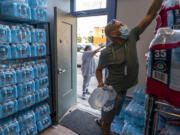 FILE - Chris Cowan with Cascadia Behavioral Healthcare's street outreach team loads water and other cooling supplies before visiting homeless camps on Aug. 12, 2021, in Portland, Ore. Oregon’s most populous county is suing more than a dozen large fossil fuel companies Thursday, June 22, 2023, to recover costs related to extreme weather events linked to climate change. The lawsuit filed in Multnomah County Circuit Court alleges the combined carbon pollution the companies emitted was a substantial factor in causing and exacerbating a 2021 heat dome, which killed 69 people in the county.