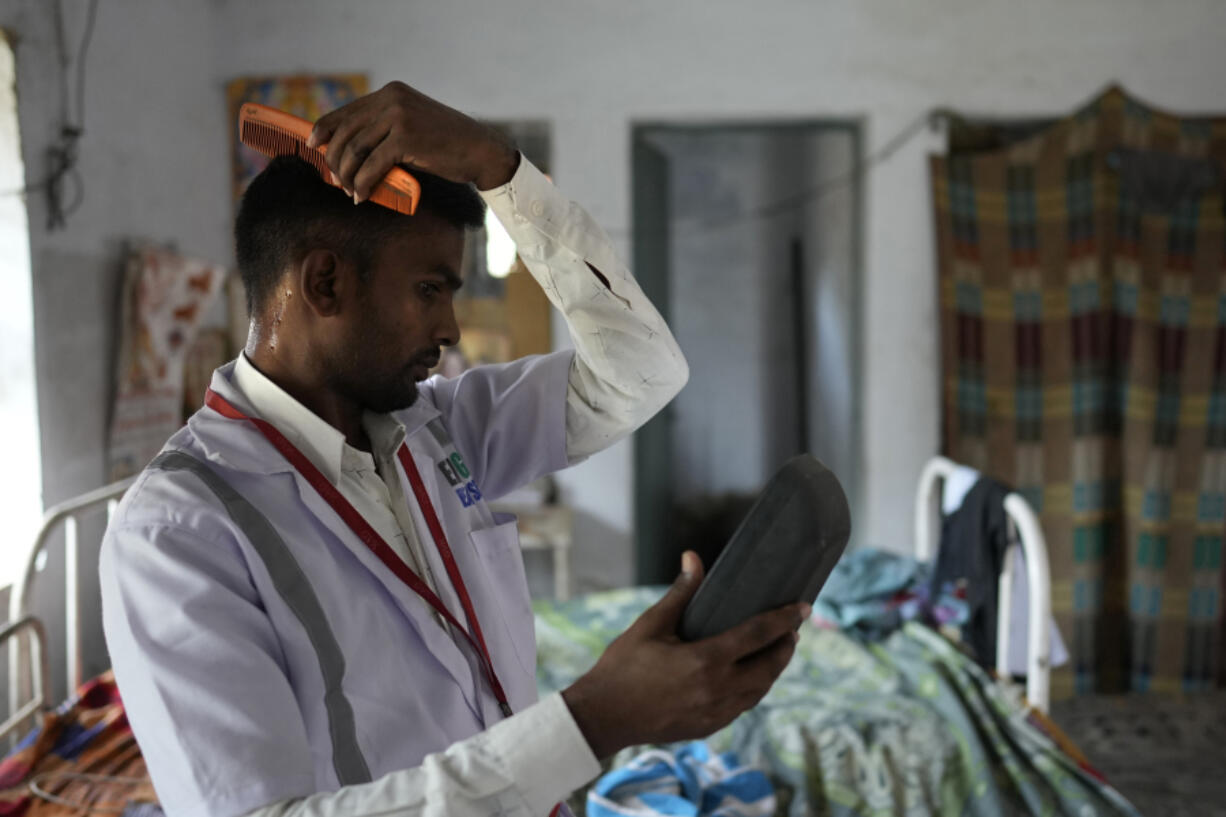 Jitendra Kumar, a paramedic who travels in an ambulance, sweats while he gets ready for duty in a room he shares with several others at the district government hospital quarters, in Banpur in the Indian state of Uttar Pradesh, Sunday, June 18, 2023. Ambulance drivers and other healthcare workers in rural India are the first line of care for those affected by extreme heat.