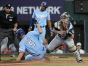 Texas Rangers' Corey Seager (5) scores on a Jonah Heim single as Seattle Mariners catcher Cal Raleigh reaches out for the throw to the plate in the first inning of a baseball game, Sunday, June 4, 2023, in Arlington, Texas. Umpire Andy Fletcher watches the play.