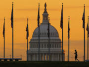 FILE - An early morning pedestrian is silhouetted against sunrise as he walks through the American flags on the National Mall with the U..S Capitol Building in the background in Washington Nov. 7, 2022. Americans on the right and left have a lot more in common than they might think -- including their strong distrust of each other. The results of the survey, conducted by NORC at the University of Chicago and the nonprofit group Starts With Us, reveal a stark truth at the source of the polarization that has a powerful grip on American politics: While most Americans agree on the core principals underlying American democracy, they no longer recognize that the other side holds those values too.(AP Photo/J.