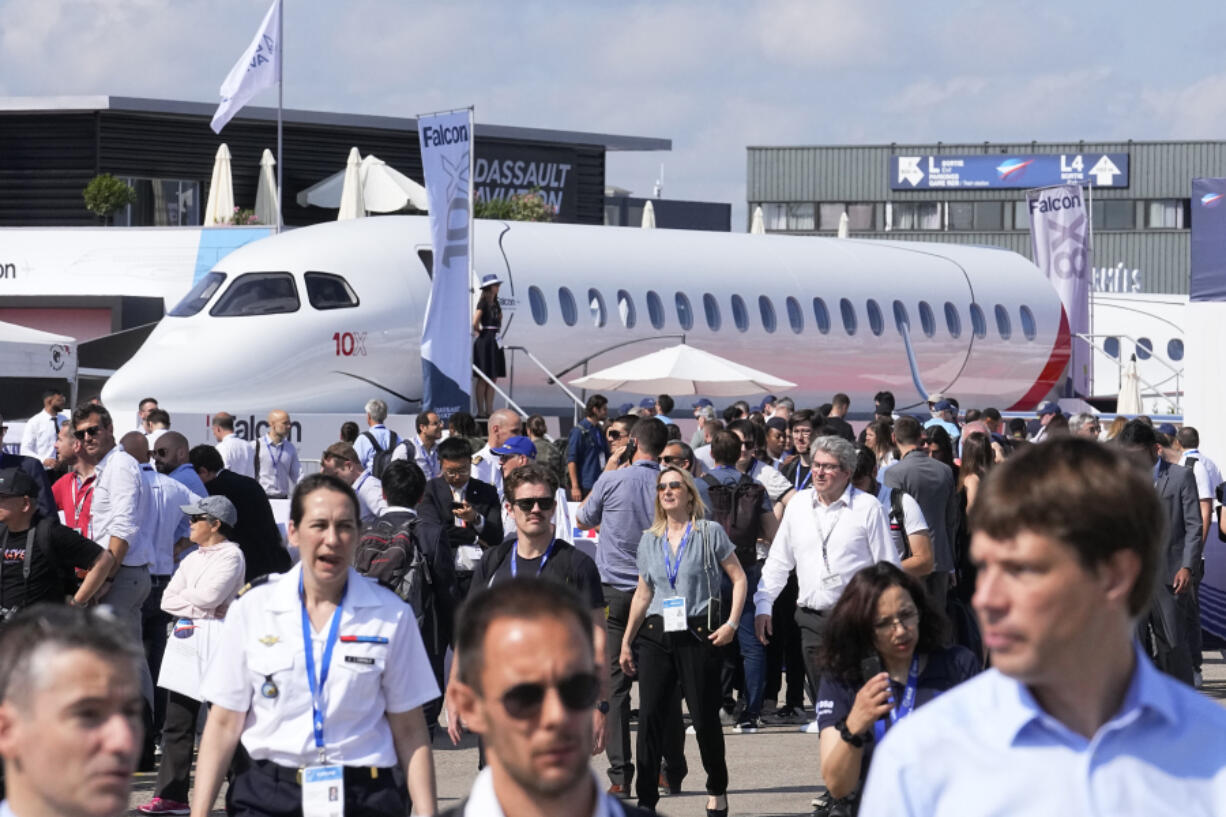 FILE - Visitors walk by a Falcon 10X prototype by the French manufacturer Dassault Aviation, at the Paris Air Show, Wednesday, June 21, 2023 in Le Bourget, north of Paris. Airlines are facing increasing pressure to cut their climate-changing emissions. That made sustainable aviation fuel a hot topic this week at the Paris Air Show, a major industry event. Sustainable fuel made from food waste or plant material is aviation's best hope for reducing emissions in the next couple of decades.