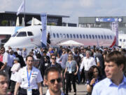 FILE - Visitors walk by a Falcon 10X prototype by the French manufacturer Dassault Aviation, at the Paris Air Show, Wednesday, June 21, 2023 in Le Bourget, north of Paris. Airlines are facing increasing pressure to cut their climate-changing emissions. That made sustainable aviation fuel a hot topic this week at the Paris Air Show, a major industry event. Sustainable fuel made from food waste or plant material is aviation's best hope for reducing emissions in the next couple of decades.