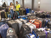 An airline employee, right, helps a traveler find her suitcase amongst the unclaimed luggage in the arrivals area of Terminal B at LaGuardia Airport, Tuesday, June 27, 2023, in New York.  Travelers waited out widespread delays at U.S. airports on Tuesday, an ominous sign heading into the long July 4 holiday weekend, which is shaping up as the biggest test yet for airlines that are struggling to keep up with surging numbers of passengers.