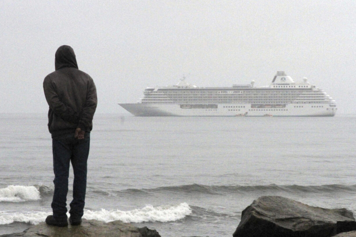 A man stands on the shore of the Bering Sea to watch the luxury cruise ship Crystal Serenity anchored just outside Nome, Alaska, in 2016.