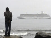 A man stands on the shore of the Bering Sea to watch the luxury cruise ship Crystal Serenity anchored just outside Nome, Alaska, in 2016.