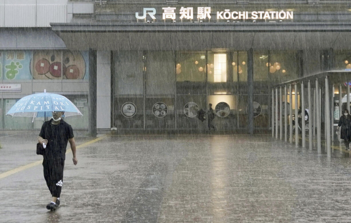 A person walks in a strong rain in Kochi, southern Japan Friday, June 2, 2023. A weakened Tropical Storm Mawar brought heavy rains to Japan's main southern islands Friday after passing the Okinawan archipelago and causing injuries to several people.