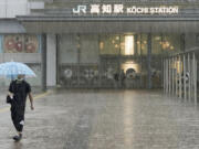 A person walks in a strong rain in Kochi, southern Japan Friday, June 2, 2023. A weakened Tropical Storm Mawar brought heavy rains to Japan's main southern islands Friday after passing the Okinawan archipelago and causing injuries to several people.