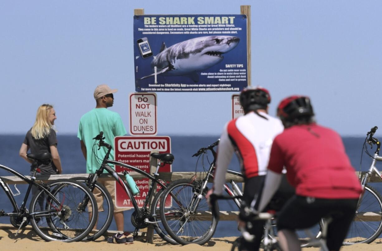 FILE - In this May 22, 2019, file photo, a shark warning warns beachgoers at Lecount Hollow Beach in Wellfleet, Mass. Scientists monitoring the white shark population in the waters off Cape Cod are stepping up their game by attaching more highly sophisticated sensors that include cameras to the predators to help keep beachgoers informed and safe, researchers said Tuesday, June 13, 2023.