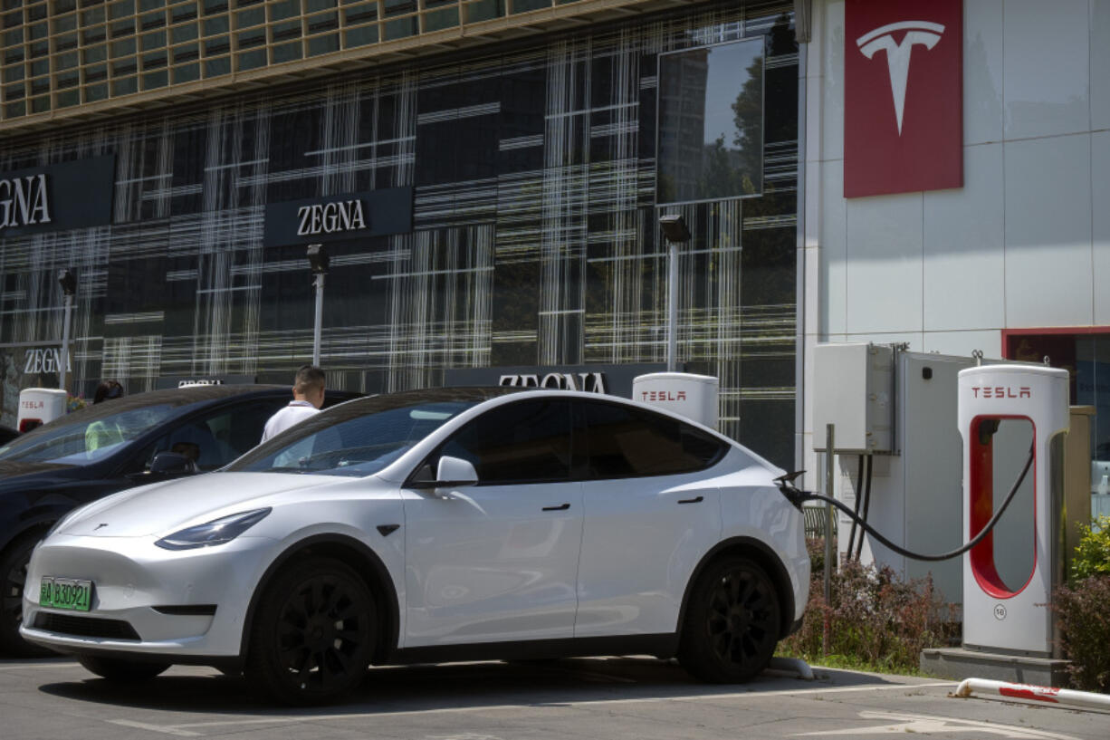 A driver gets into his car at an electric vehicle charging station outside of a Tesla dealership in Beijing, Saturday, June 24, 2023. Threatened by possible shortages of lithium for electric car batteries, automakers are racing to lock in supplies of the once-obscure "white gold" in a politically and environmentally fraught competition from China to Nevada to Chile.