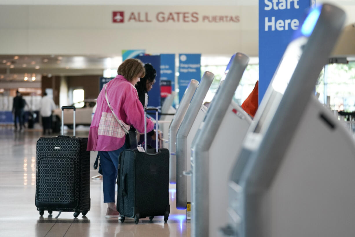 FILE - Travelers use the kiosk by the ticketing gate as they prepare for travel from Love Field airport, May 19, 2023, in Dallas. Lawmakers are considering rolling back an Obama-era rule that requires airlines to show the total price of a ticket upfront in advertising, while also tweaking training requirements for airline pilots and making other changes in a massive bill covering the Federal Aviation Administration.