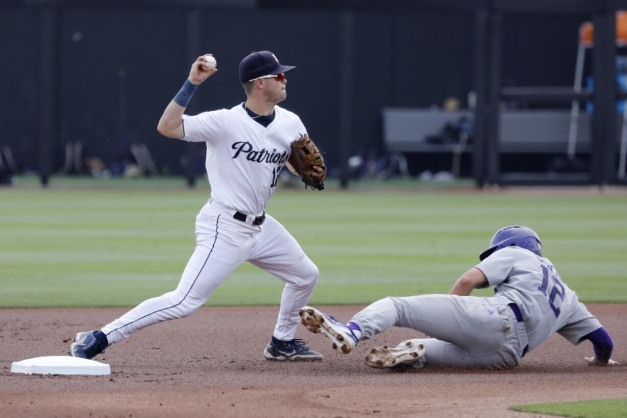 Dallas Baptist's Luke Hefner throws to first base after tagging out Washington's Cam Clayton during an NCAA baseball game on Friday, June 2, 2023, in Stillwater, Okla.