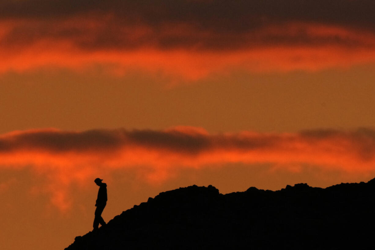 A person is silhouetted against the sky at sunset at Papago Park in Phoenix on Thursday, March 2, 2023.  The homicide rate for older U.S. teenagers rose to its highest point in nearly 25 years during the COVID-19 pandemic, and the suicide rate for adults in their early 20s was the worst in more than 50 years, government researchers said Thursday, June 15.