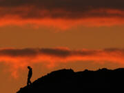 A person is silhouetted against the sky at sunset at Papago Park in Phoenix on Thursday, March 2, 2023.  The homicide rate for older U.S. teenagers rose to its highest point in nearly 25 years during the COVID-19 pandemic, and the suicide rate for adults in their early 20s was the worst in more than 50 years, government researchers said Thursday, June 15.