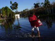 FILE - Jose Cruz, 13, carries an empty Jerrycan through receding flood waters outside his house as his family heads out to look for supplies, three days after the passage of Hurricane Ian, in Fort Myers, Fla., Oct. 1, 2022. After months of gradually warming sea surface temperatures in the tropical Pacific Ocean, NOAA officially issued an El Nino advisory Thursday, June 8, 2023, and stated that this one might be different than the others.