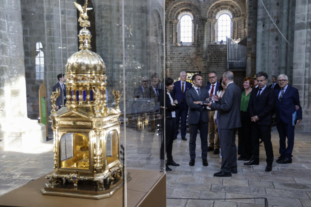 France's President Emmanuel Macron, center, visits a exhibition tracing the site's encyclopedic history via 30 objects in Le Mont-Saint-Michel, north-western France, Monday, June 5, 2023. France's mystical sea-surrounded abbey at Mont-Saint-Michel, a major tourist draw and UNESCO heritage site, celebrates its 1000th birthday.