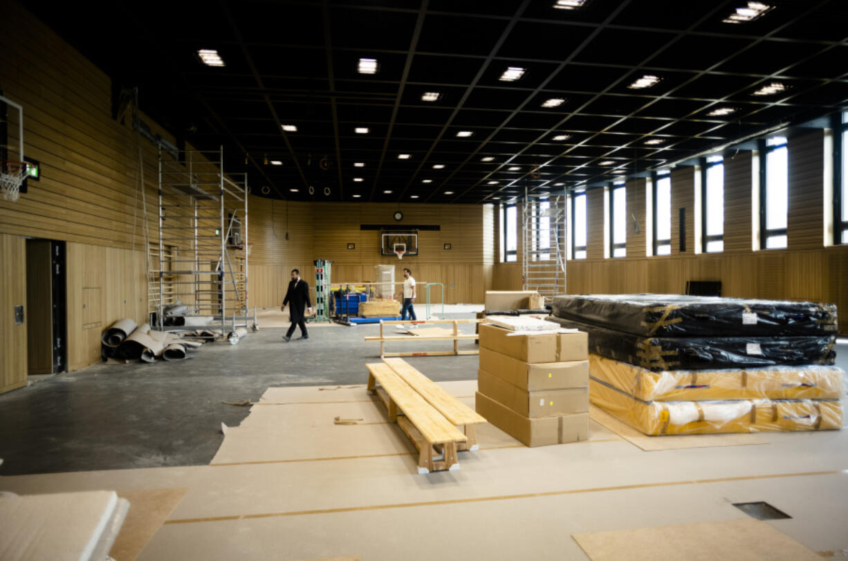 Rabbi Yehuda Teichtal, left, walks through the construction site of a huge indoor basketball court and gym that can be turned into a lecture hall for up to 600 people or a reception hall for weddings and bar mitzvahs, inside the new Jewish educational and cultural complex in Berlin, Germany, Monday, June 12, 2023. The Pears Jewish Campus, run by the local Chabad community, is located in the German capital's Wilmersdorf neighbourhood and will be officially opened Sunday, June 25, 2023.