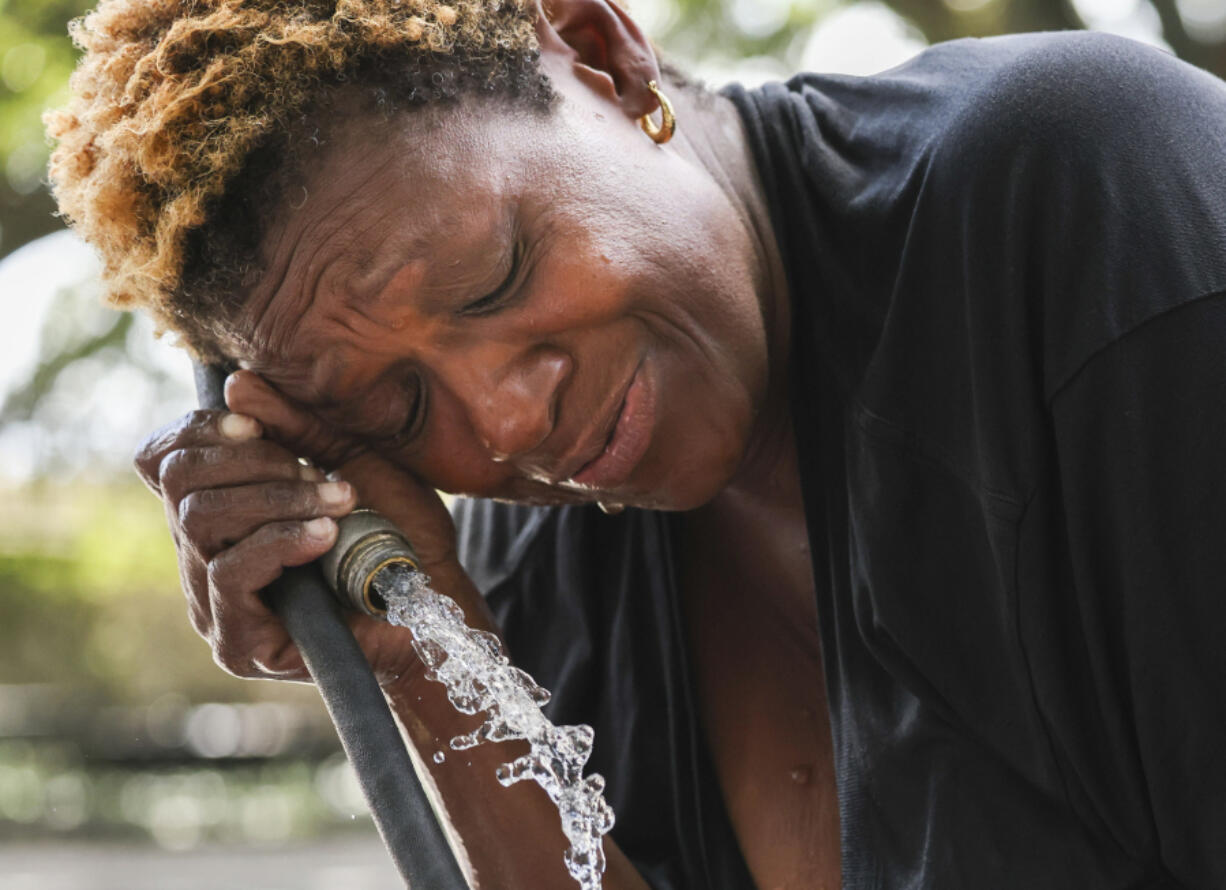 Judy Breland Morris cools off and washes herself off with a hose after she claims she was maced near Jackson Square, during an excessive heat warning in New Orleans, Tuesday, June 27, 2023.