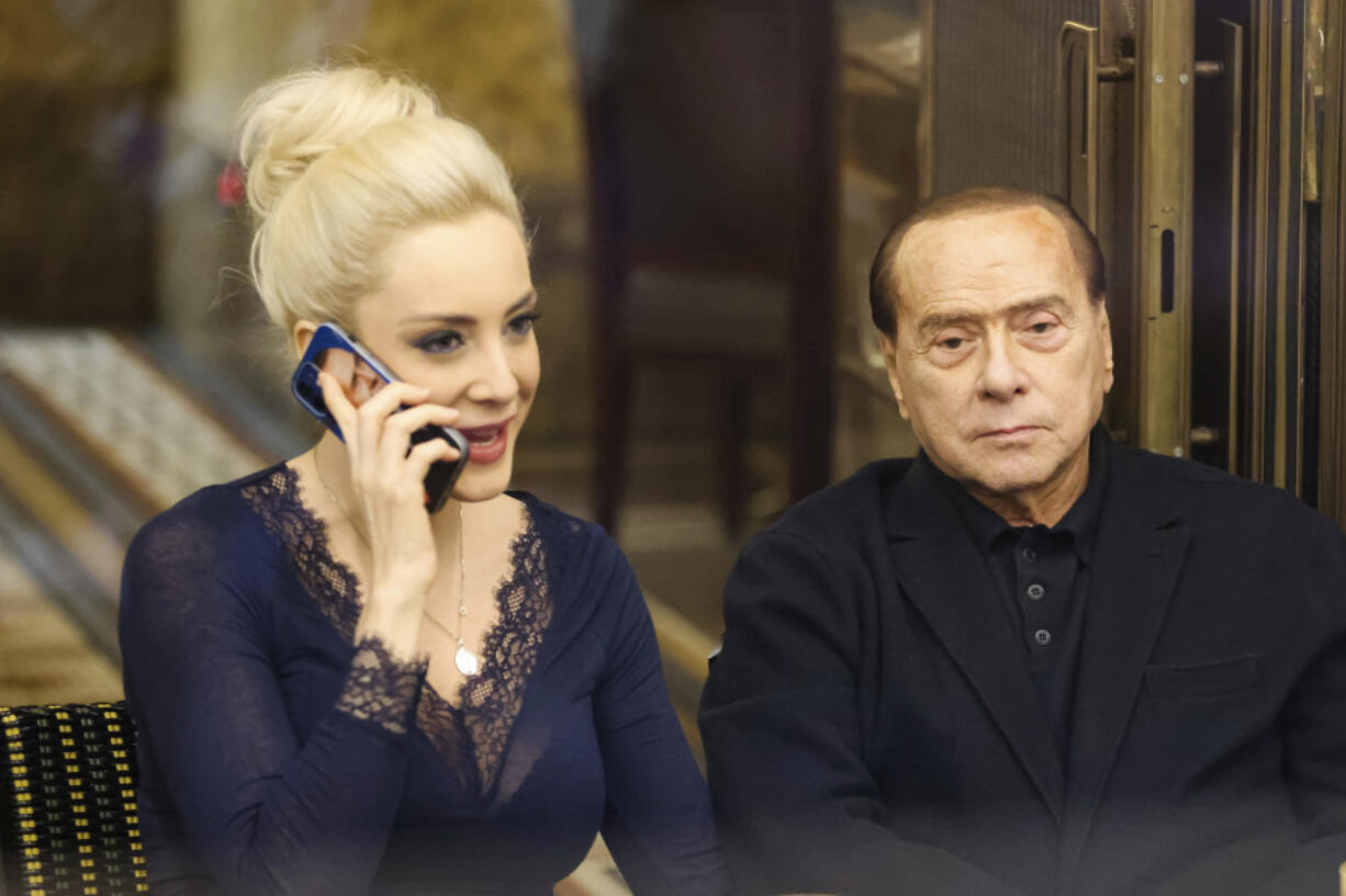 Silvio Berlusconi, right, and his partner Marta Fascina are pictured in Milan, Italy, on Feb. 25, 2022. Italian media are reporting that Silvio Berlusconi, the boastful billionaire media mogul who was Italy's longest-serving premier despite scandals over his sex-fueled parties and allegations of corruption and bribery, has died at age 86.