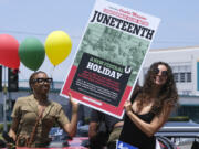 People hold a sign in their car during a car parade to mark Juneteenth on June 19, 2021, in Inglewood, Calif. Communities all over the country will be marking Juneteenth, the day that enslaved Black Americans learned they were free. (Ringo H.W.