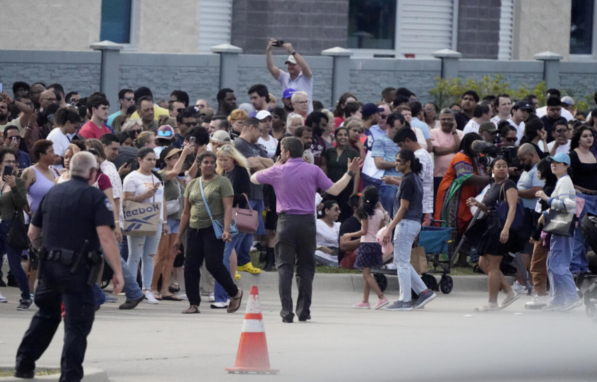 FILE - People gather across the street from a shopping center after a shooting May 6, 2023, in Allen, Texas. Police released video footage Wednesday, June 28, of an officer killing a neo-Nazi gunman, quickly ending the shooting that left eight people dead and seven others wounded at the mall. The edited five-and-a-half-minute video details the final moments of Mauricio Garcia, 33, after he unleashed a rain of bullets from an AR-15-style rifle.