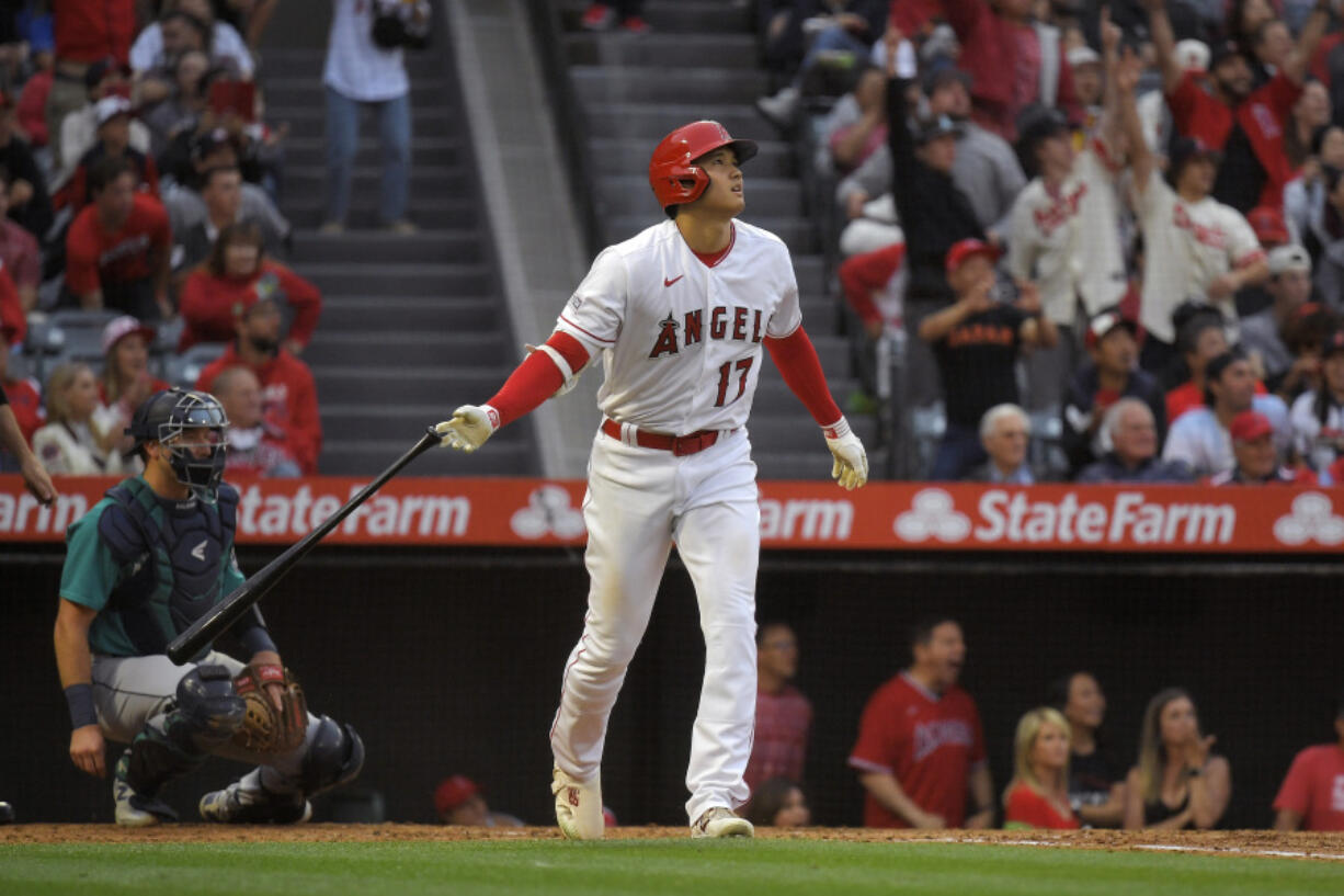 Los Angeles Angels' Shohei Ohtani drops his bat after hitting a two-run home run as Seattle Mariners catcher Cal Raleigh watches during the third inning of a baseball game Friday, June 9, 2023, in Anaheim, Calif. (AP Photo/Mark J.