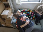 Brady Hill gets a hug from his mother Cathrine after breakfast at their home in Meridian, Idaho, June 19, 2023. Brady survived a rare brain cancer as a baby, but requires round the clock care. Brady's sister Misha watches. Families of severely disabled children across the country are worried about the future of crucial Medicaid payments they started receiving to provide care during the COVID-19 pandemic.