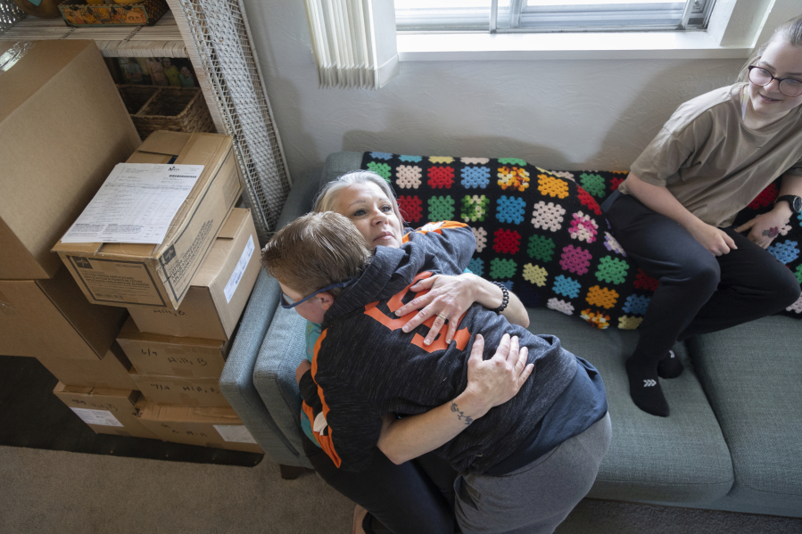 Brady Hill gets a hug from his mother Cathrine after breakfast at their home in Meridian, Idaho, June 19, 2023. Brady survived a rare brain cancer as a baby, but requires round the clock care. Brady's sister Misha watches. Families of severely disabled children across the country are worried about the future of crucial Medicaid payments they started receiving to provide care during the COVID-19 pandemic.