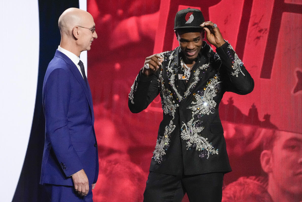 Scoot Henderson, right, dons a Portland Trail Blazers hat with NBA Commissioner Adam Silver watching after being selected third overall by the Blazers during the NBA basketball draft, Thursday, June 22, 2023, in New York.