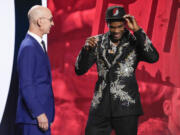 Scoot Henderson, right, dons a Portland Trail Blazers hat with NBA Commissioner Adam Silver watching after being selected third overall by the Blazers during the NBA basketball draft, Thursday, June 22, 2023, in New York.