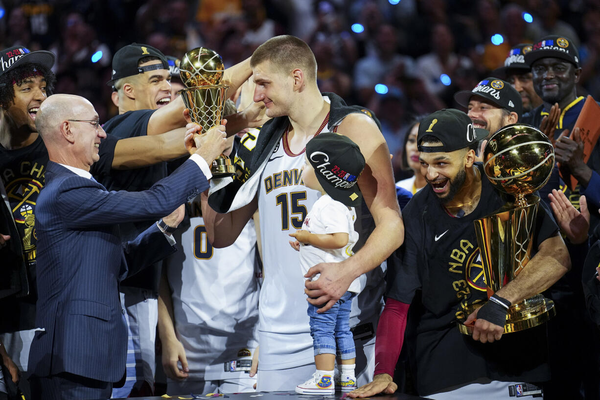 Commissioner Adam Silver, left, hands the MVP award to Denver Nuggets center Nikola Jokic, center, after the team won the NBA Championship with a victory over the Miami Heat in Game 5 of basketball's NBA Finals, Monday, June 12, 2023, in Denver.