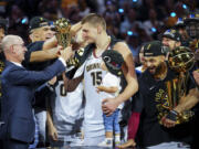 Commissioner Adam Silver, left, hands the MVP award to Denver Nuggets center Nikola Jokic, center, after the team won the NBA Championship with a victory over the Miami Heat in Game 5 of basketball's NBA Finals, Monday, June 12, 2023, in Denver.