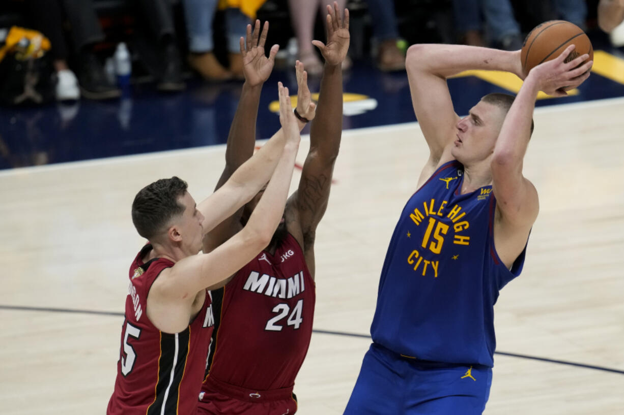 Denver Nuggets center Nikola Jokic, right, shoots over Miami Heat forwards Duncan Robinson, left, and Haywood Highsmith during the first half of Game 1 of basketball's NBA Finals, Thursday, June 1, 2023, in Denver.