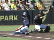 Oral Roberts utility Jonah Cox, left, slides home to score past Oregon catcher Bennett Thompson, right, during a NCAA super regional game Sunday in Eugene, Ore.