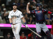 Seattle Mariners' Jarred Kelenic walks away after striking out, while Washington Nationals catcher Riley Adams throws the ball back during the 11th inning of a baseball game Tuesday, June 27, 2023, in Seattle. The Nationals won 7-4.