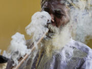 Ras Jah, a member of the Ras Freeman Foundation for the Unification of Rastafari, smokes cannabis from a chalice pipe during service May 14 in the tabernacle in Liberta, Antigua.