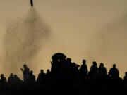 Water mist is sprayed on Muslim pilgrims as they pray on the rocky hill known as the Mountain of Mercy, on the Plain of Arafat, during the annual Hajj pilgrimage, near the holy city of Mecca, Saudi Arabia, Tuesday, June 27, 2023. Around two million pilgrims are converging on Saudi Arabia's holy city of Mecca for the largest Hajj since the coronavirus pandemic severely curtailed access to one of Islam's five pillars.