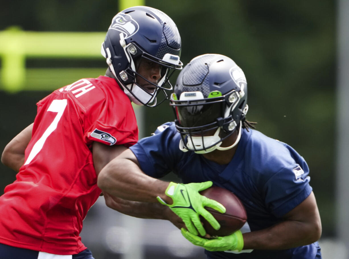 Seattle Seahawks quarterback Geno Smith (7) hands off to running back Kenneth Walker III, Monday, May 22, 2023, at the team's NFL football training facility in Renton, Wash.