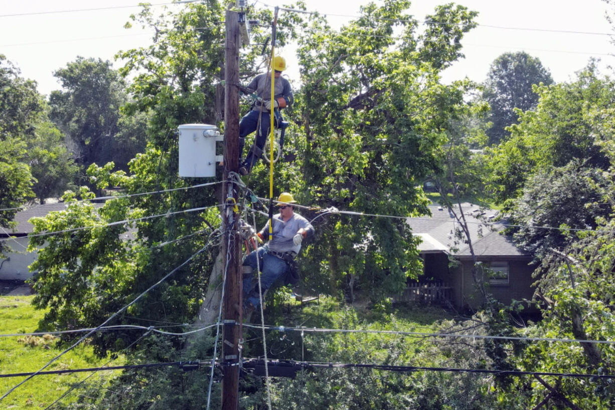 Workers on a utility pole tend to the power lines after the weekend storms left many in the city without power Thursday, June 22, 2023, in Tulsa, Okla.