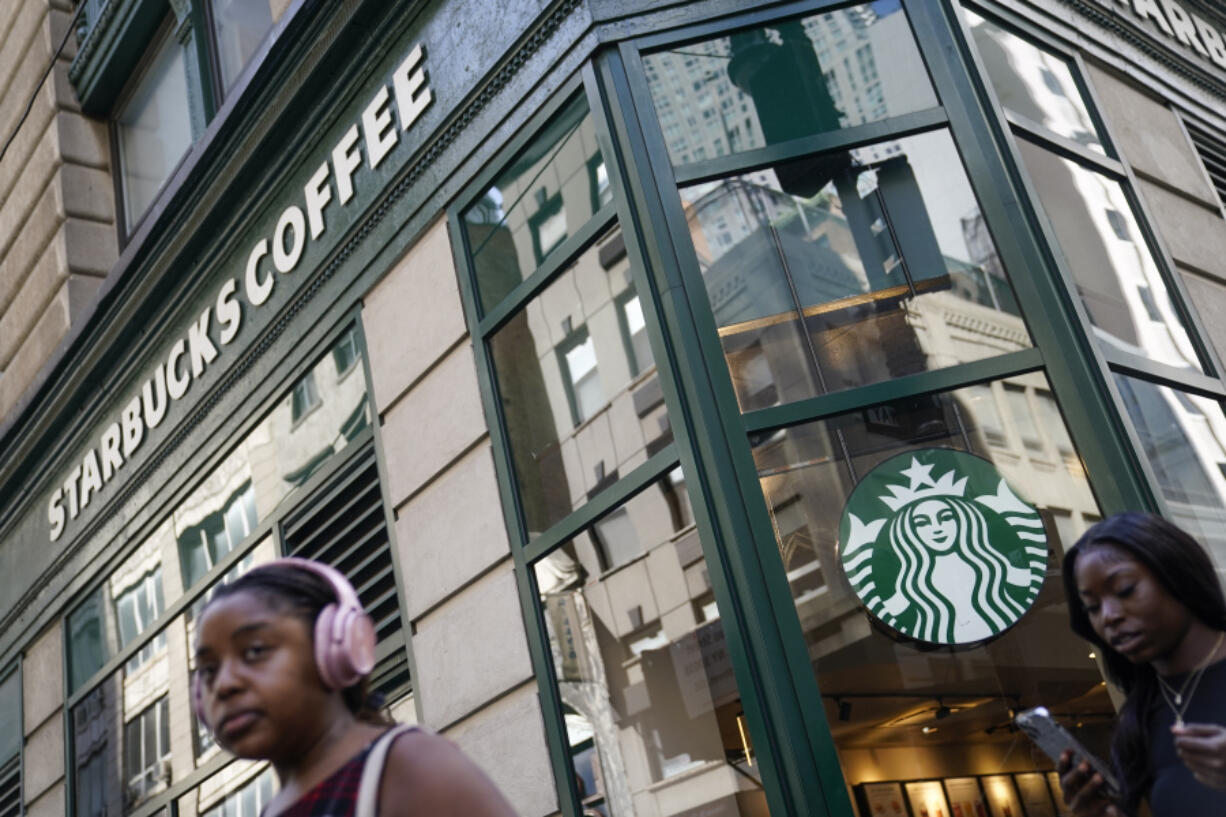 Pedestrians pass a Starbucks in the Financial District of Lower Manhattan, Tuesday, June 13, 2023, in New York. Starbucks is denying union organizers' claims that it banned LGBTQ+ Pride displays in its U.S. stores after Target and other brands experienced backlash. The Seattle coffee giant says there has been no change to its policy and it encourages store leaders to celebrate Pride in June.