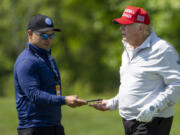 FILE - Walt Nauta, left, takes a phone from Former President Donald Trump during the LIV Golf Pro-Am at Trump National Golf Club, May 25, 2023, in Sterling, Va.  Nauta is set to be arraigned on charges that he helped the former president hide classified documents that the Justice Department wanted back.  Nauta was charged earlier this month alongside Trump in a 38-count indictment filed by Justice Department special counsel Jack Smith.